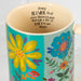 A mug adorned with a bright floral pattern, showcasing an array of colorful flowers and intricate designs.