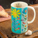 A mug featuring a colorful floral design, showcasing a variety of flowers in a bright and cheerful pattern.