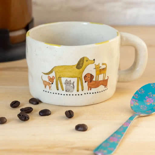 A coffee cup sits beside a dog, with a spoon resting on the table, creating a cozy café scene.