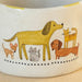A steaming coffee cup next to a playful dog, with a spoon placed nearby, evokes a warm, inviting atmosphere.
