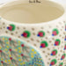 A decorative ceramic mug adorned with a bright, colorful chicken illustration.