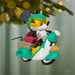 Decorative ornament of a character on a scooter with a blurred Christmas tree background