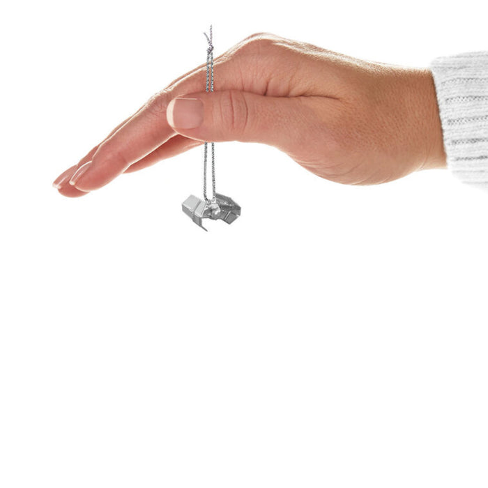 Hand holding a  Mini  Hallmark Ornament of a  Star wars TIE fighter on a white background