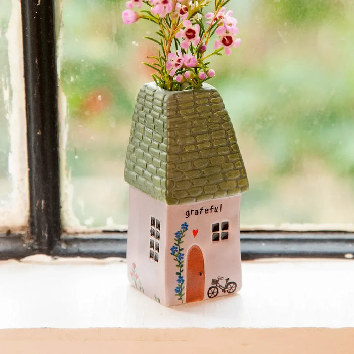 A small house surrounded by vibrant pink flowers in the garden.