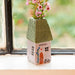 A small house surrounded by vibrant pink flowers in the garden.