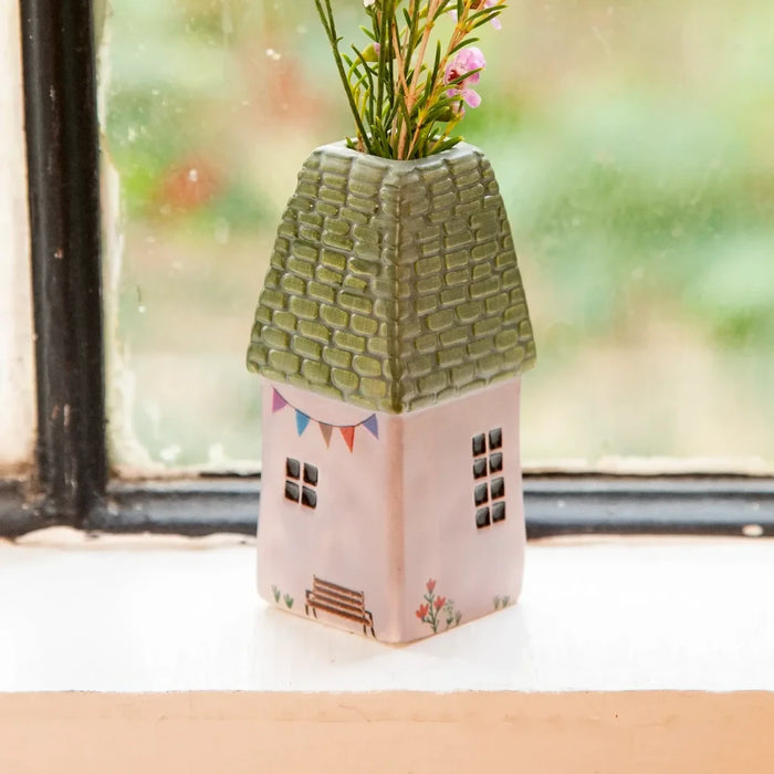 A quaint house adorned with blooming pink flowers in the yard.