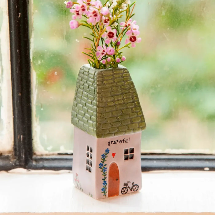 A charming house featuring a garden filled with pink flowers.