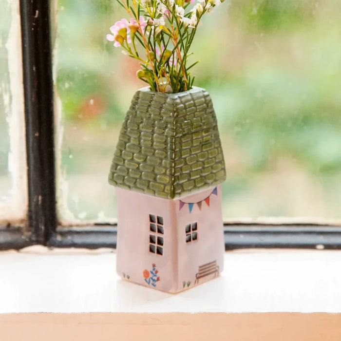 A cozy house nestled among colorful pink flowers in the landscape.