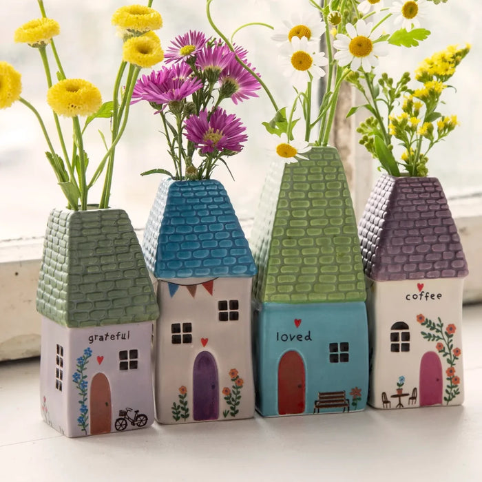 A petite house with a flourishing display of pink flowers nearby.
