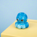 Blue checkered plush toy on a yellow surface with a light blue polka dot background