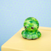 Green plush octopus toy on a yellow surface with a light blue background