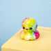 Colorful tie-dye octopus toy on a yellow surface with a light blue background