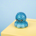 Blue octopus plush toy on a yellow surface with a light blue polka dot background