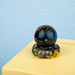 Decorative glass octopus with black speckled ball on a yellow surface against a blue polka dot background