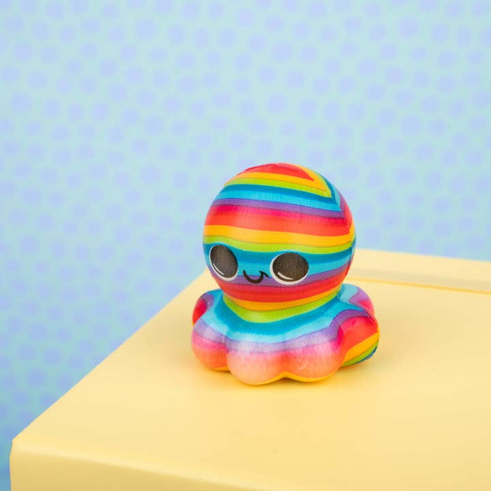 Colorful striped toy on a yellow surface with a light blue background