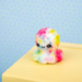 Colorful tie-dye plush toy on a yellow surface with a light blue background