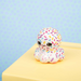 Plush toy octopus with colorful sprinkles on a yellow surface against a light blue background