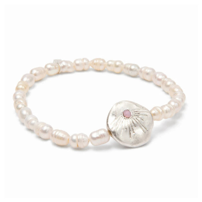 A delicate bracelet adorned with shimmering pearls, representing love, resting on a textured surface.