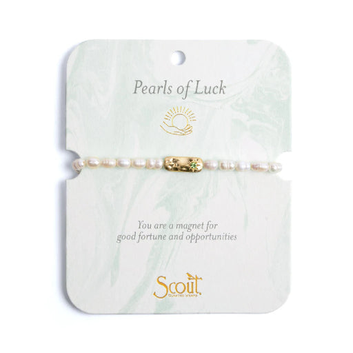 Elegant bracelet featuring pearls, symbolizing luck and charm, displayed on a soft fabric background.