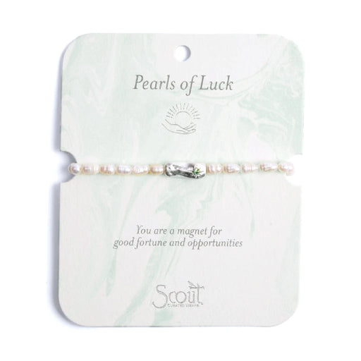 Elegant bracelet featuring pearls, symbolizing luck and charm, displayed on a soft fabric background.
