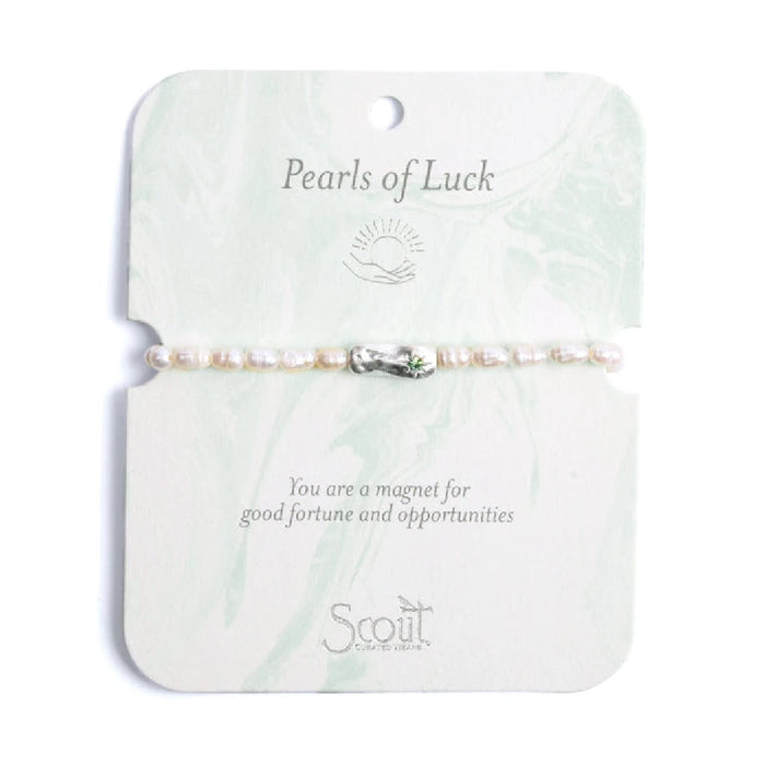Elegant bracelet featuring pearls, symbolizing luck and charm, displayed on a soft fabric background.