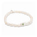 A delicate bracelet adorned with pearls, representing good fortune, resting on a textured surface.
