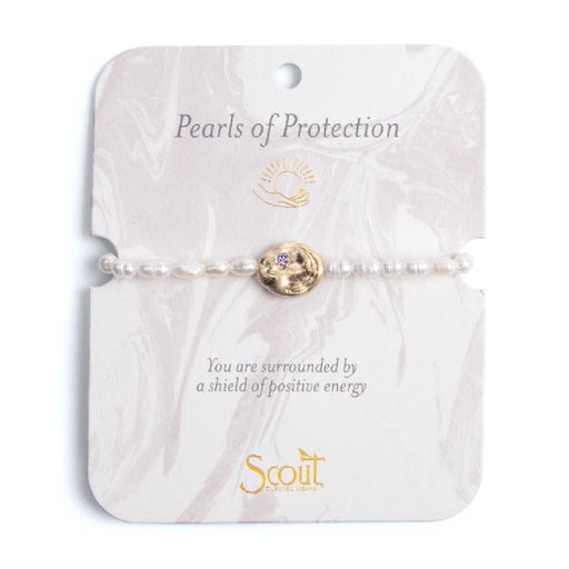 Elegant bracelet featuring pearls, symbolizing protection and beauty, displayed on a soft fabric background.