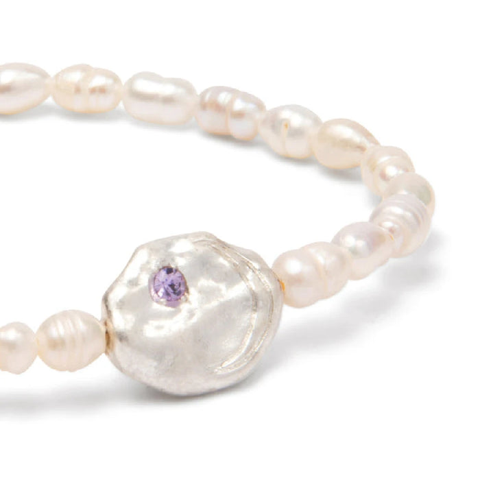 A delicate bracelet made of white pearls, highlighted by a purple stone.