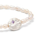 A delicate bracelet made of white pearls, highlighted by a purple stone.