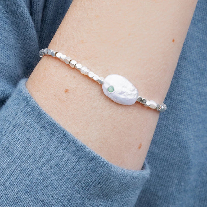A delicate bracelet composed of white pearls and green stones, combining classic and modern elements beautifully.