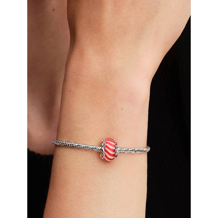 Pandora Candy Murano Glass Charm displayed on a silver Pandora bracelet worn on a wrist, showing red and white peppermint swirl design.