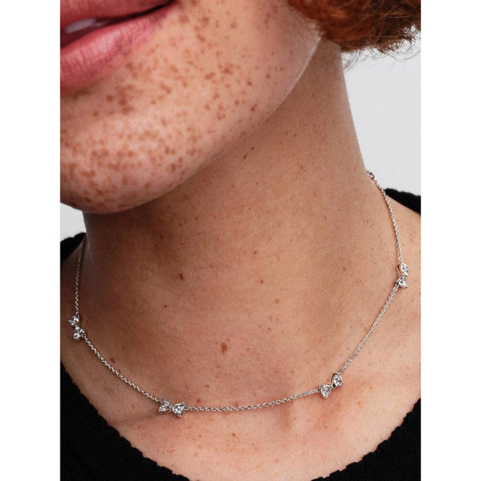 Close-up of a woman wearing the Pandora Clear Bow Station Chain Necklace, showcasing the delicate sterling silver chain with sparkling bow-shaped stations.