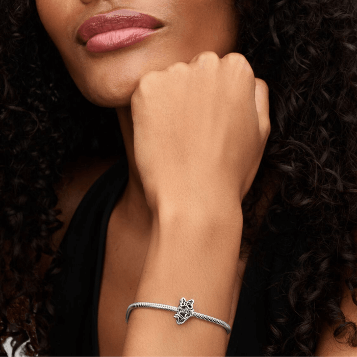 Close-up of woman wearing Pandora Disney Daisy Duck Openwork Charm on sterling silver bracelet showcasing playful Disney style.