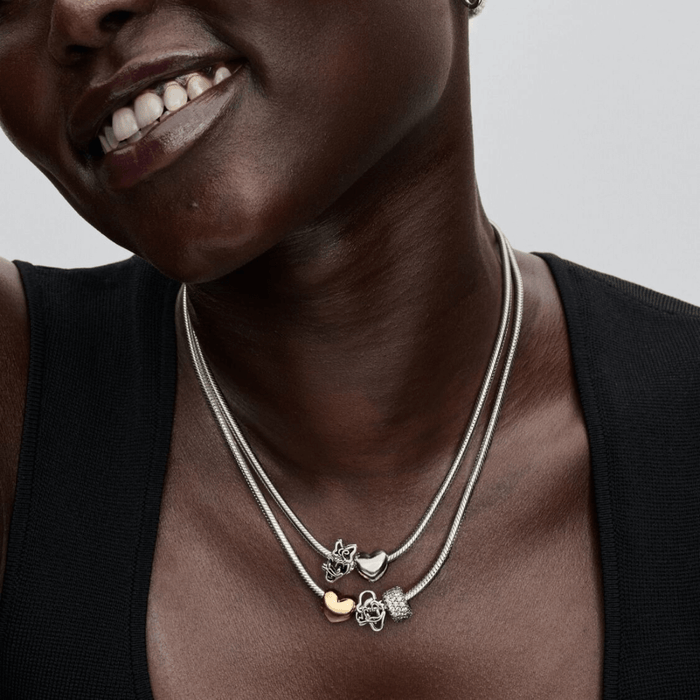 Woman wearing layered Pandora Disney necklaces with Daisy Duck and Mickey Mouse Openwork Charms in sterling silver and heart charms.