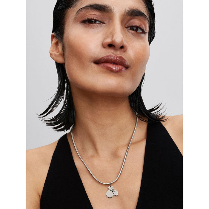 Model wearing the Pandora Disney Minnie Mouse Dangle Charm on a silver necklace.