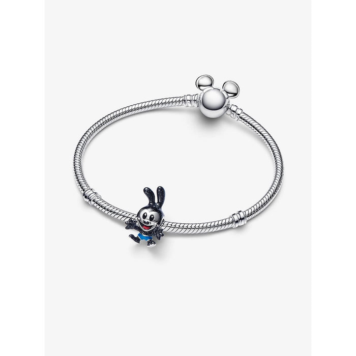 The Oswald charm styled on a silver snake chain bracelet with a round Mickey Mouse-shaped clasp, showcasing how the charm looks when worn on a bracelet.