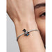 A close-up of a person’s wrist wearing a silver bracelet with the Pandora Disney Oswald the Lucky Rabbit charm. The charm is detailed in black enamel with blue shorts, featuring Oswald’s signature long ears and cheerful pose.
