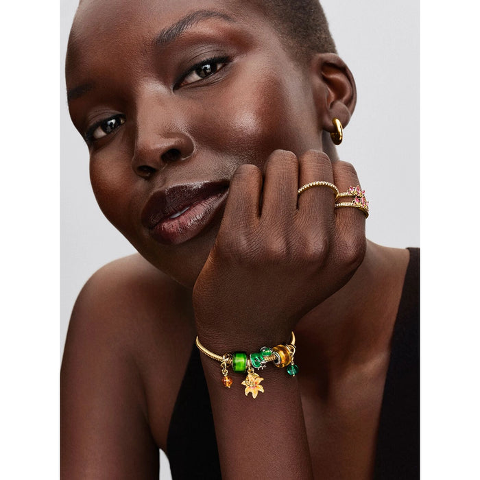 Disney Rapunzel Sun Flower charm paired with green and gold Pandora charms on Moments bracelet.