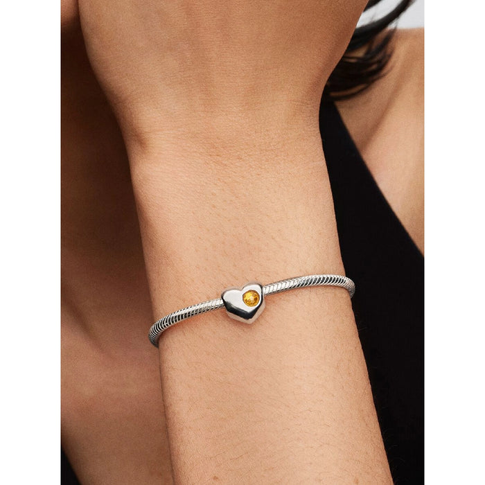 Woman wearing Pandora Honey Stone Heart Charm on silver bracelet.