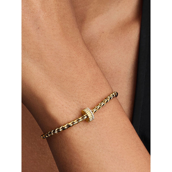 Close-up of a gold bracelet worn on the wrist featuring the Pandora Ribbed Clip Charm with clear pavé stones.