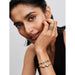 Woman wearing Pandora silver woven bracelet stacked with gold and silver charms and rings.