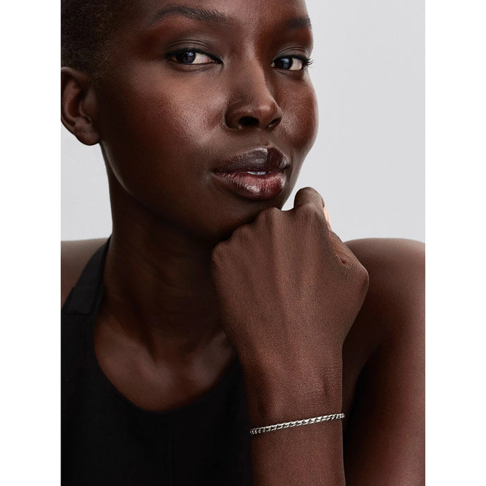Woman wearing Pandora silver woven bracelet with sleek round clasp, styled with black top.