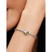 Woman wearing a Pandora bracelet with the Spring Green Stone Heart Charm in sterling silver and green crystal.