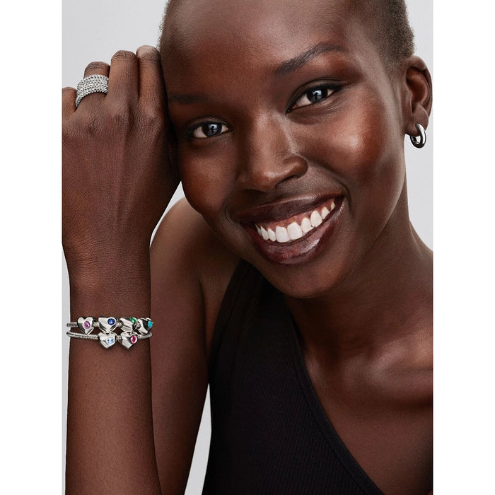 Model wearing stacked Pandora bracelets with multiple heart charms including the sea aqua blue stone design.