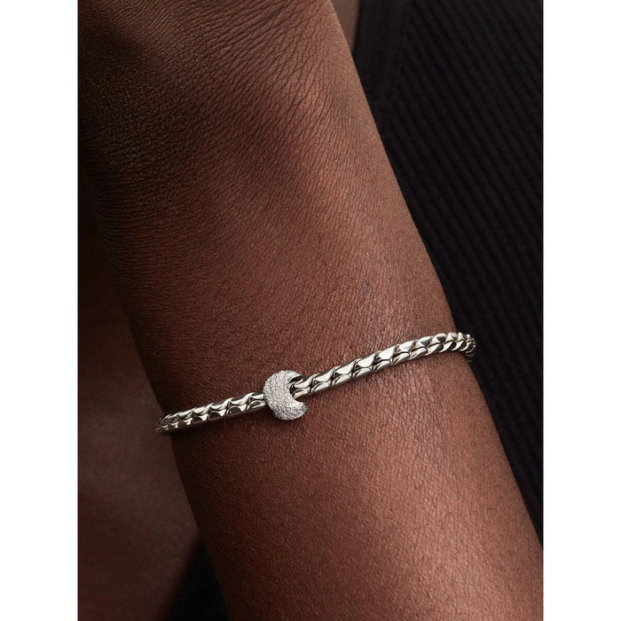 Pandora Textured Moon Mini Charm worn on a silver woven bracelet, displayed on a person’s wrist for scale and styling inspiration.