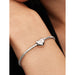 Sterling silver Pandora bracelet with a heart-shaped charm featuring a white stone, shown worn on a wrist.