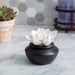 Decorative white flower on a black base on a marble surface with a blurred background