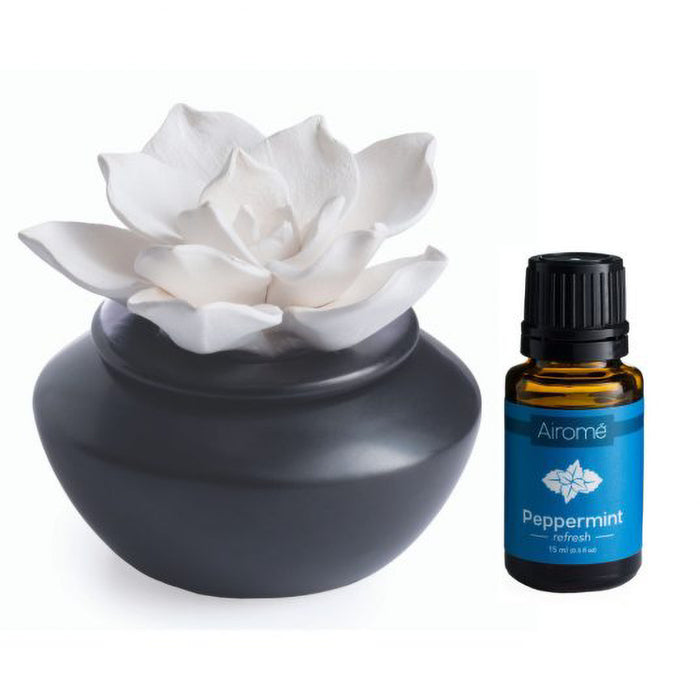 Aromatherapy diffuser with white flower and Airome peppermint essential oil bottle on a white background