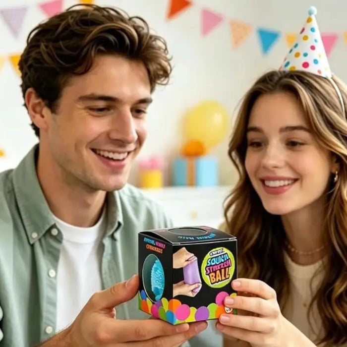 Man and woman holding a colorful ball toy with a box, surrounded by party decorations.