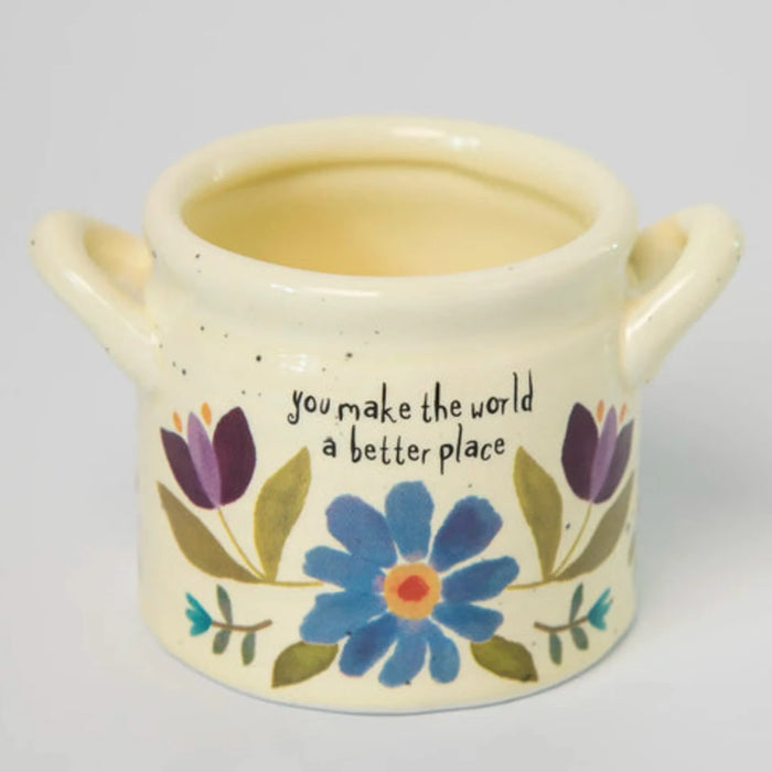 A woman displays a small ceramic pot with a healthy succulent plant, highlighting her passion for plants and home decor.